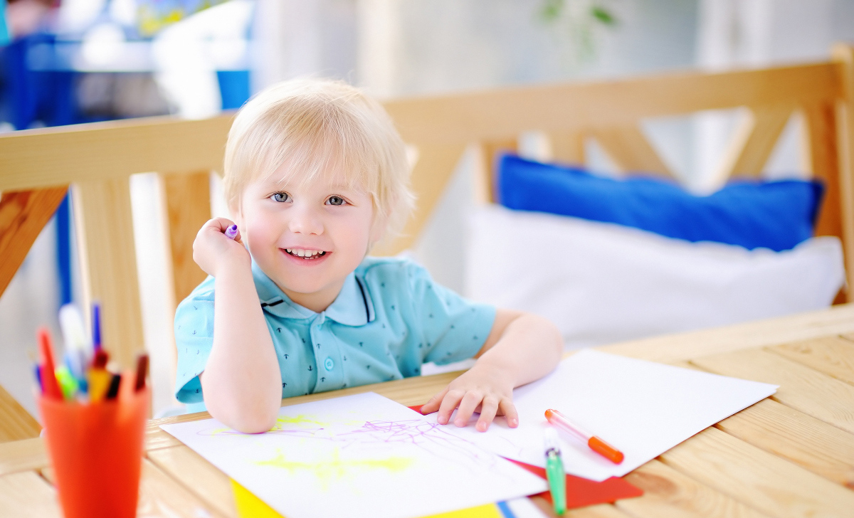 Cute little boy drawing and painting with colorful markers pens at kindergarten. Creative kid painting at playschool. Development toys for preschooler children